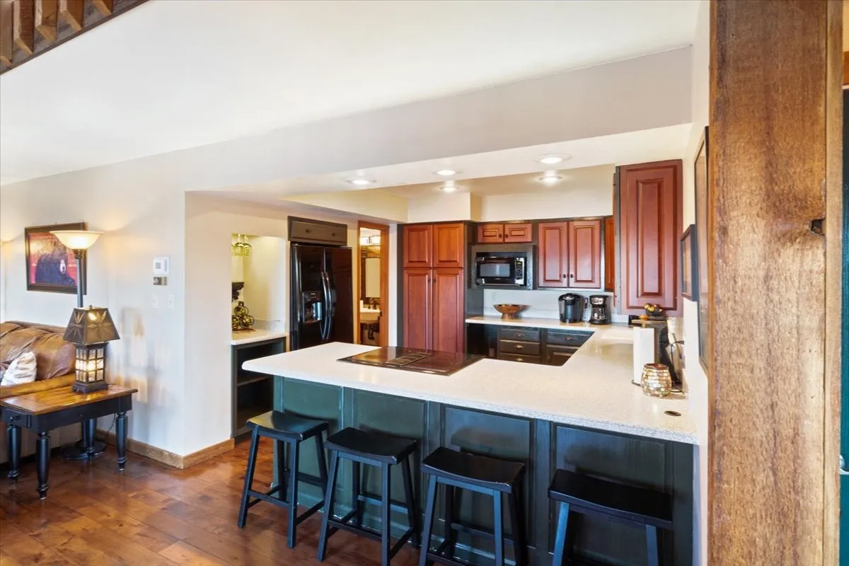 A stylish kitchen featuring a large island with wooden cabinetry, comfortable seating, and inviting lighting fixtures. The space is arranged to accommodate both cooking and gathering, with seamless flow for helpers and guests.