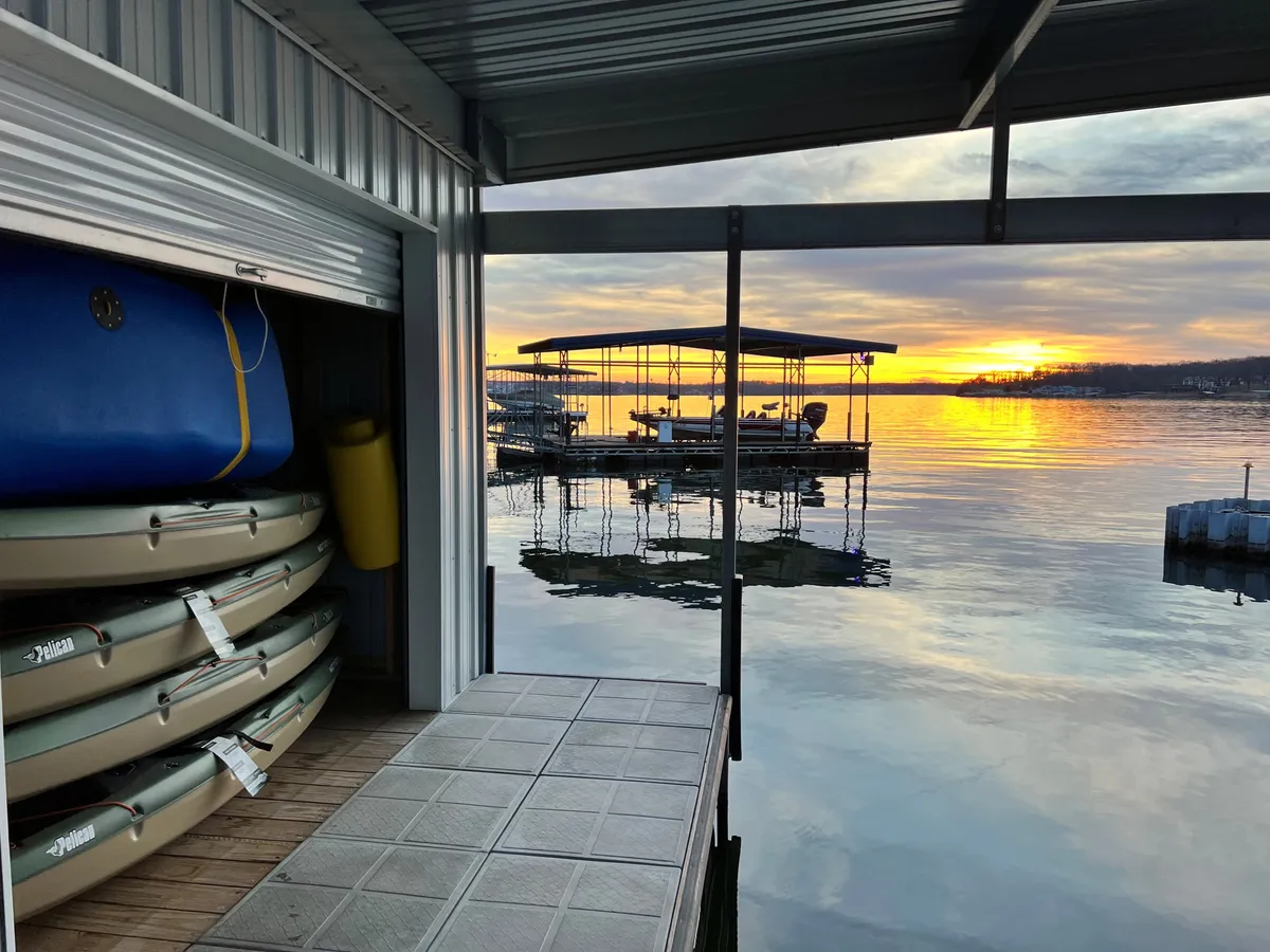 This image captures kayaks docked on the water at sunset, with the private docking area clearly visible. The tranquil lake reflects the colors of the sky, and the setup highlights water sports equipment and ample dockside space for relaxing or launching boats and kayaks.