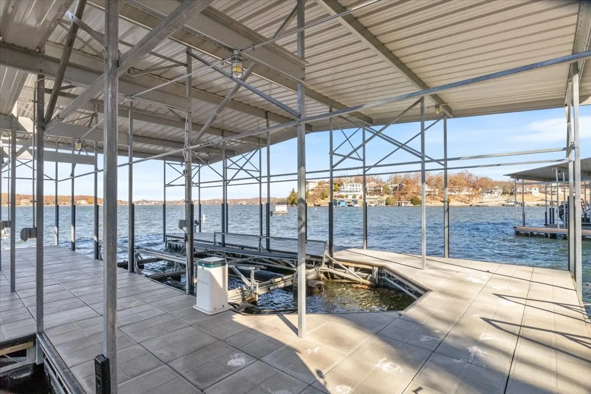 A tranquil exterior shot of a waterfront dock, with the structural framework visible and boats in the distance. The water is calm, suggesting a setting ideal for launching kayaks, paddle boards, or simply relaxing after a day of water sports.