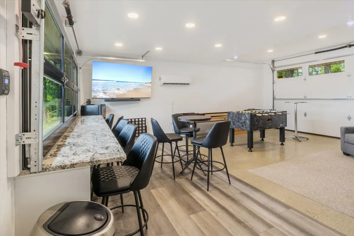 A vibrant game room interior is outfitted with a foosball table, bar seating, a large screen, and comfortable lounge space, creating an inviting atmosphere for playful tournaments, movie marathons, and socializing after a day outdoors.