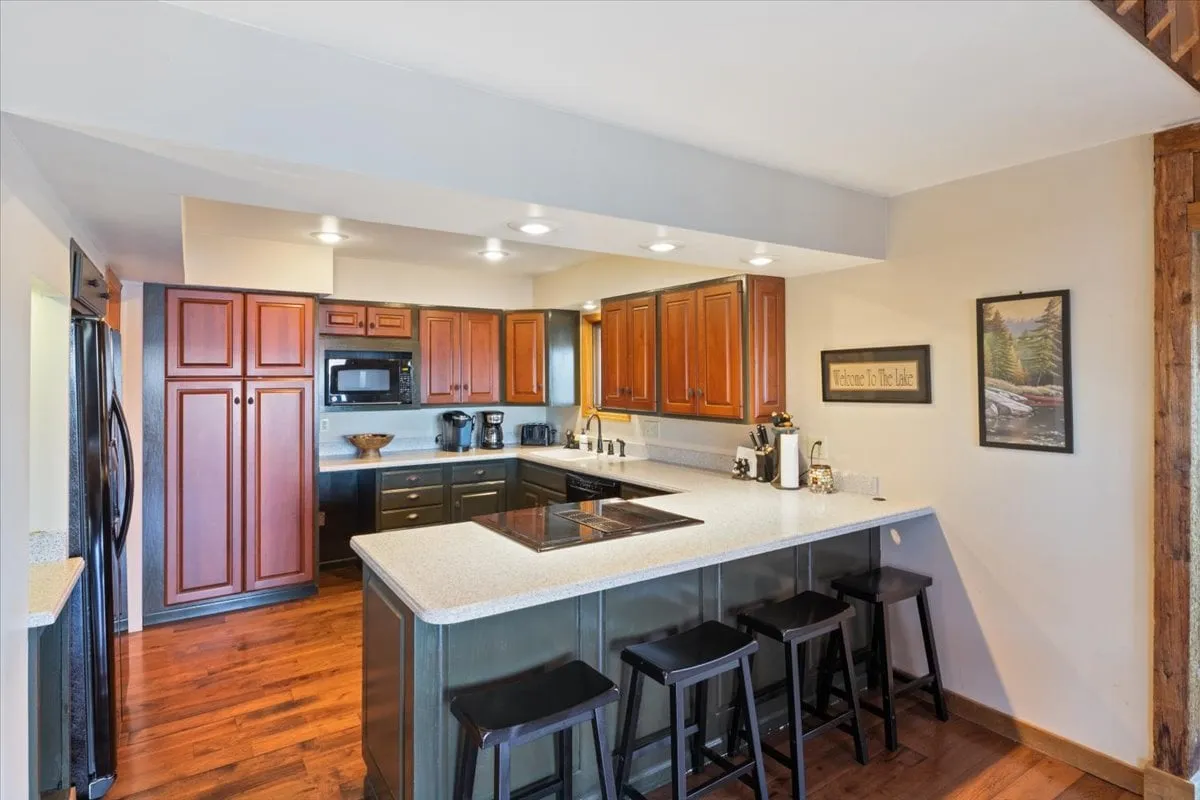 A welcoming kitchen with a spacious island, bar stools for casual seating, ample cabinetry, and modern appliances set against a warm backdrop. The space is open and inviting, designed for both meal preparation and social interaction.