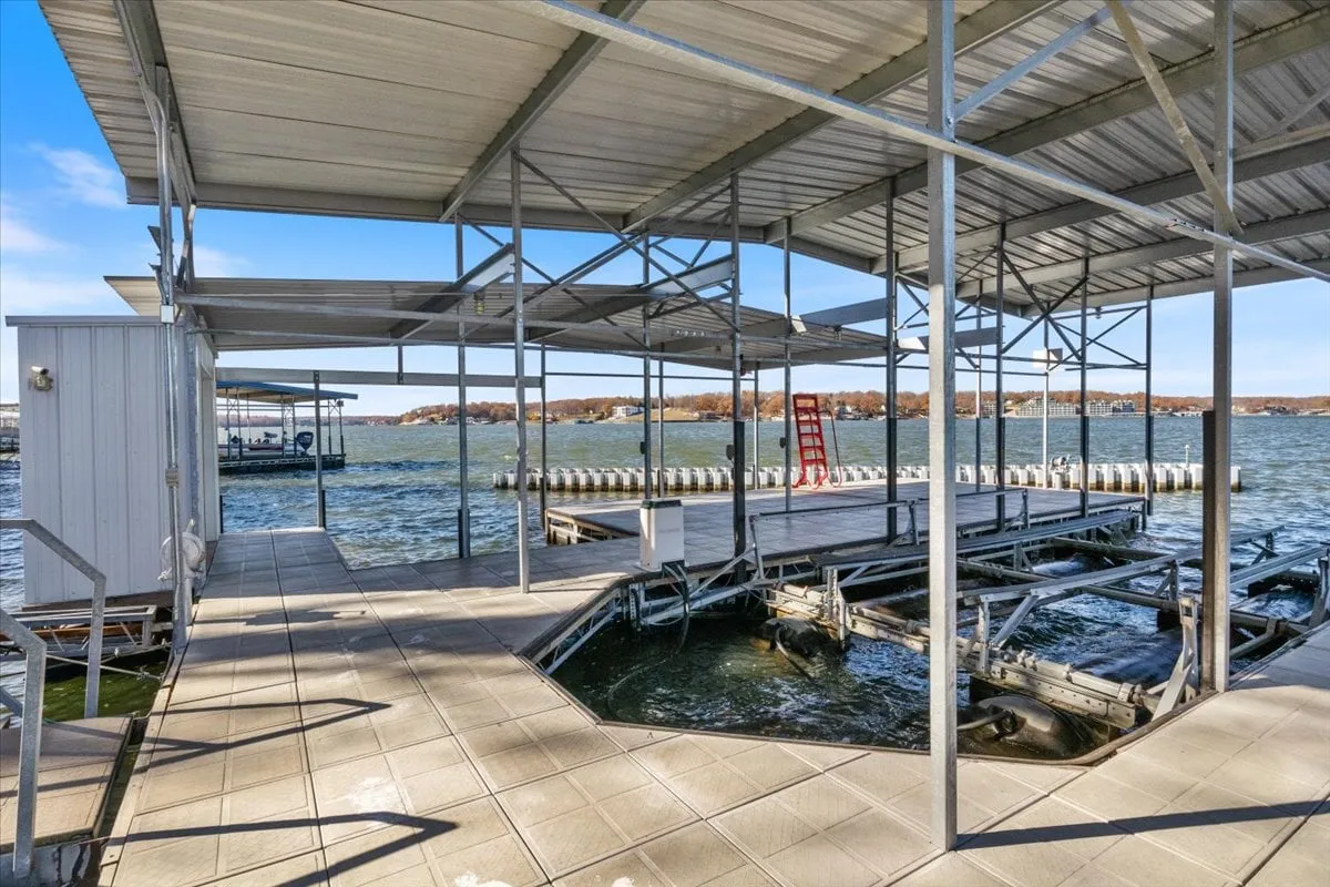 A tranquil, wide-angle exterior shot that showcases the dock, boathouse, and open waterfront. The warm glow of the sunset reflects on the still waters, evoking feelings of relaxation and the perfect setting for sunset cocktails or launching a kayak adventure.
